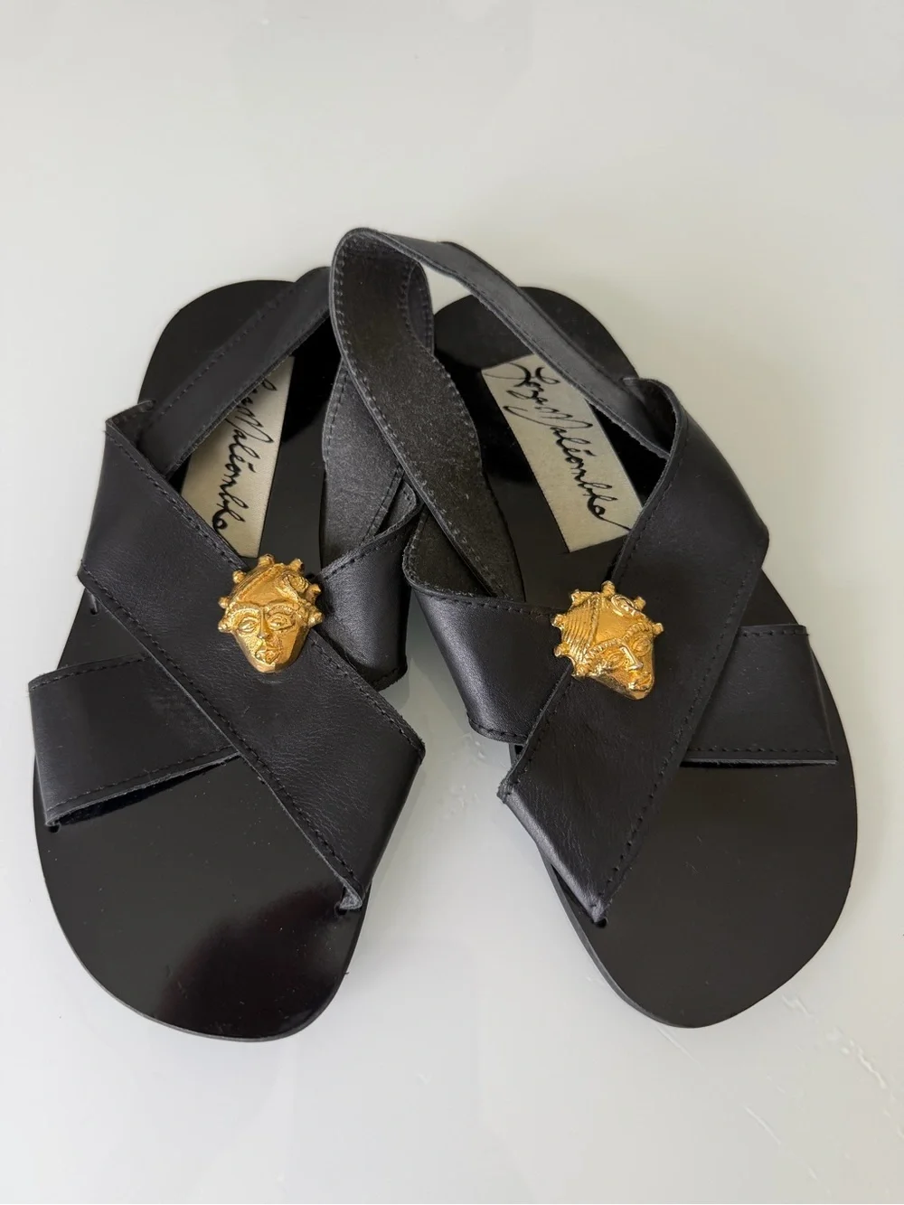Black Leather Cross-Strap Sandals with Gold Medallion Accent